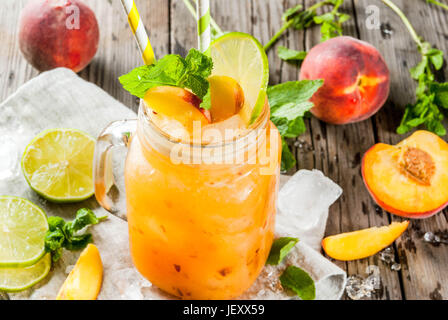 Summer drinks, cocktails. Vegan food. Peach smoothies, juice or lemonade. In a mason jar, with lime, chopped ice and mint leaves. On an old rustic woo Stock Photo