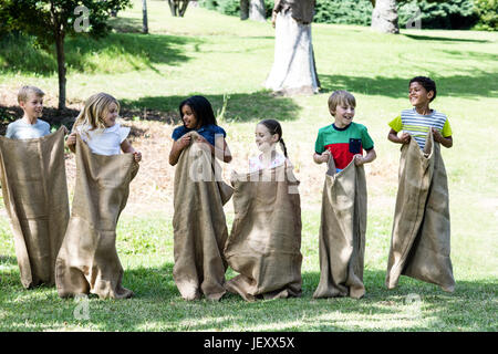 Children having a sack race in park Stock Photo