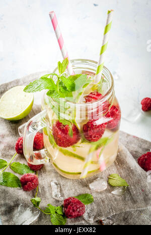 Summer drinks, cocktails. Vegan food. Infused detox water with lime, mint and fresh organic raspberries. On light concrete table, Copy space Stock Photo