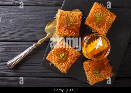 Delicious Middle Eastern pastries with pistachios and fresh honey close-up on a plate. horizontal view from above Stock Photo