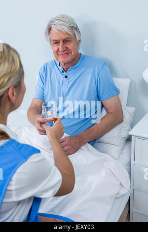 Nurse giving medicins to senior man at home Stock Photo