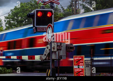 Train passing a level crossing with red traffic lights flashing, railroad crossing Czech Republic, Europe Stock Photo