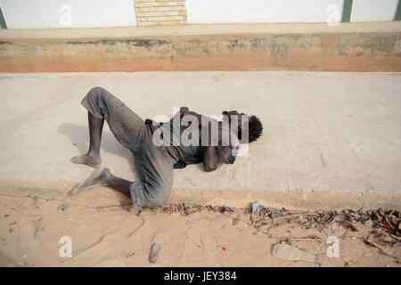 Drunk man is sleeping on the pavement in Dakar, Senegal. Stock Photo