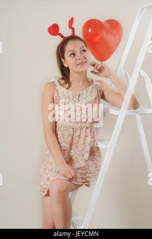 cute beautiful girl dreaming about Valentine's day on stairs, happy holiday concept Stock Photo