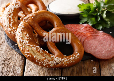 German appetizer: sliced salami and pretzels with sauce close-up on the table. Horizontal Stock Photo