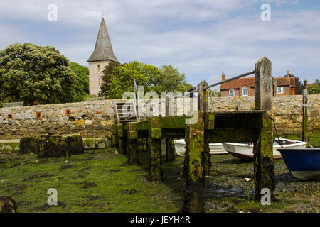 A small wooden jetty covered with barnacles and seaweed in the harbour at Bosham village in West sussex in the South of England Stock Photo