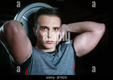 Young athletic man holding weights in studio. Serious facial expression. Stock Photo