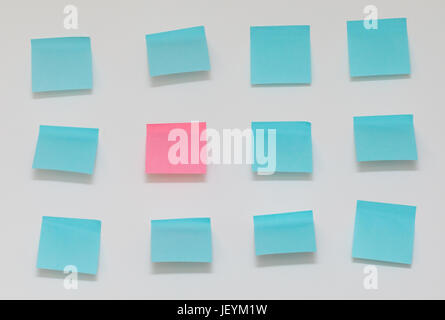Single pink post it note in sea of blue post it notes Stock Photo