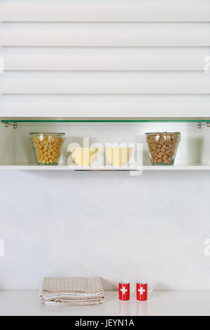 Food ingredients organized on a shelf on modern kitchen countertop. White simple kitchen. Stock Photo
