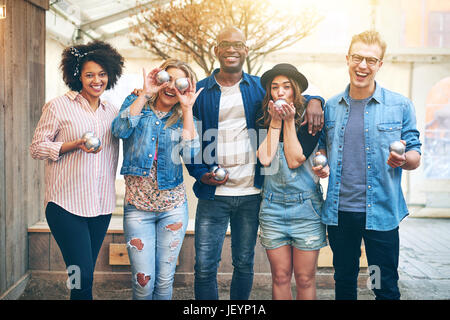 Expressive multiethnic group of friends spending time together and posing with petanque balls. Stock Photo
