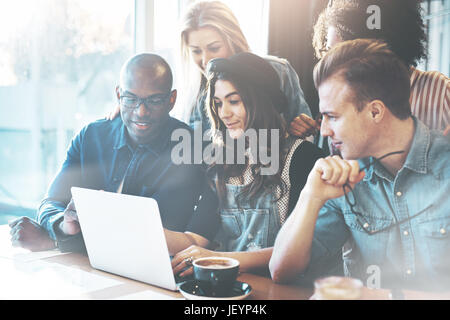 Multiracial business team made of determined young people looking at a laptop while working together in a modern office Stock Photo