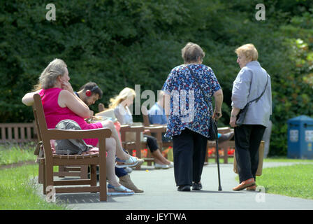 senior citizens or old people seniors in Glasgow Scotland walking overweight in park with stick or aid Stock Photo