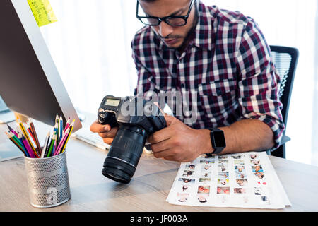 Side view of photographer working at desk Stock Photo