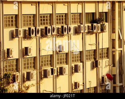 building wall with many air conditioners and red satellite dishes Stock Photo
