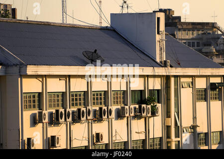 building wall with many air conditioners and parabolic satellite dishes on the rooftops Stock Photo