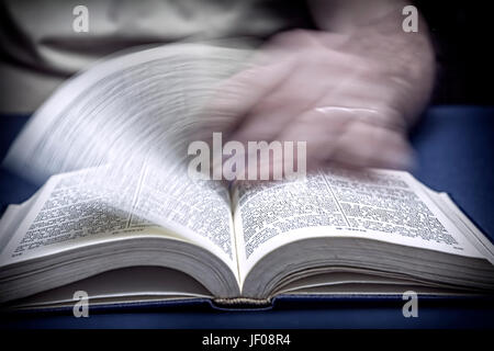 Man turns the page in an old little bible or book Stock Photo