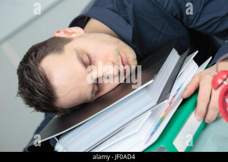 Man asleep on stack of folders Stock Photo