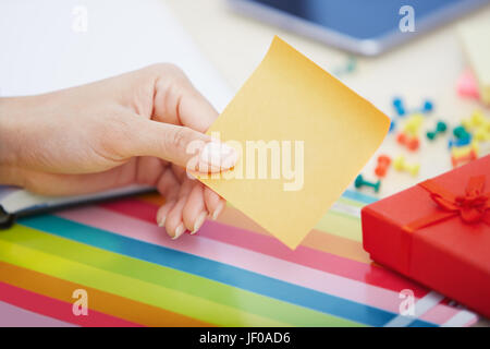Hand of woman with blank adhesive note Stock Photo