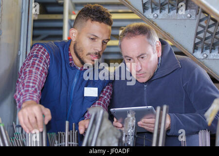 workers checking metal pipes in a warehouse Stock Photo