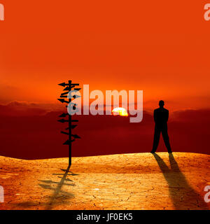 conceptual image of silhouetted directional sign and businessman on cracked dry landscape over sunset Stock Photo