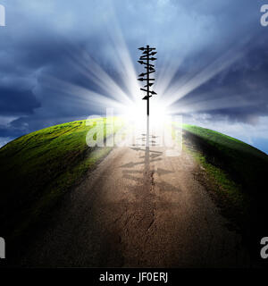 conceptual image of silhouetted directional sign on empty road over cloudy sky with beam of light Stock Photo