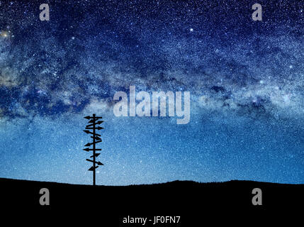conceptual image of silhouetted directional sign and abstract lights of universe. NASA galaxy images manipulated and used; https://nasasearch.nasa.gov Stock Photo