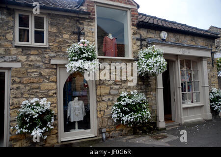 Hanging Baskets at Millers Tale Clothing and Knitwear Shop in the Market Town of Helmsley, Ryedale, North Yorkshire Moors National Park, England, UK. Stock Photo