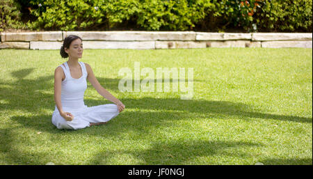 Lovely young woman meditating in the garden Stock Photo