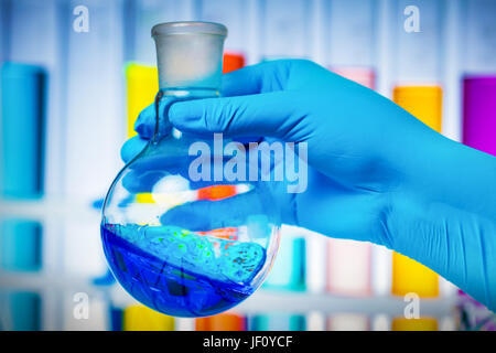 Scientist's hand holding a test tube filled with coloured liquid. Experiment and laboratory glassware. Stock Photo
