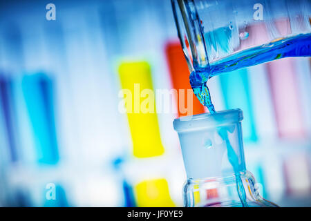 Pouring colorful liquid from tube to a flask. Chemical experiment and laboratory equipment. Stock Photo