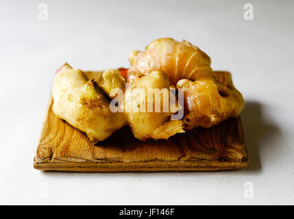 Fresh ginger on a wooden board against a white background. Stock Photo