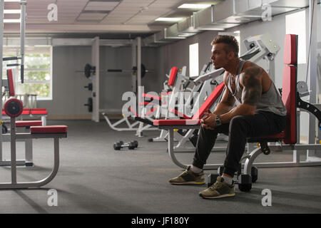 Handsome tattooed bodybuilder posing in gym Stock Photo
