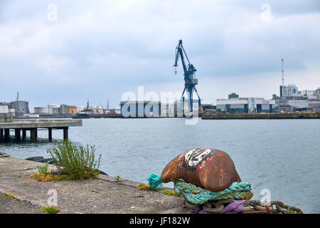 Mooring post on the quay of Aarhus in Denmark, with a gantry crane and warehouses in the background Stock Photo