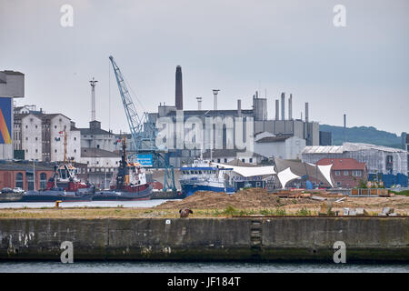 AARHUS, DENMARK - JUNE 05, 2016: Look to a messy harbor area with ships, crane and old dirty industrial buildings Stock Photo