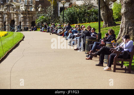 LONDON, ENGLAND, UK - APRIL 24 2017 : unidentified people relax in the park lunch break. Is widespread eating lunch in one of the city parks during the beautiful days . Stock Photo