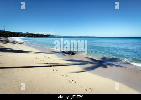 Beautiful white sand beach with turquoise colour sea and shadows of palm trees on Saud beach. A beautiful curve in the beach stretches to the horizon Stock Photo