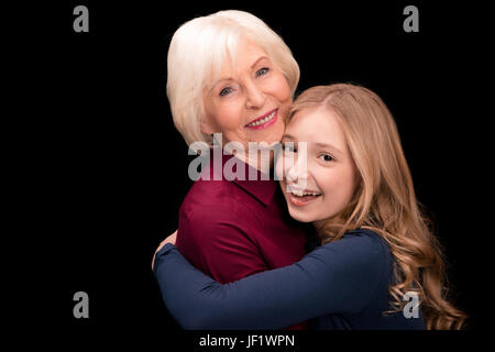 happy grandchild and grandmother hugging isolated on black in studio Stock Photo