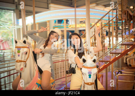 beautiful sisters with family sightseeing trip going to the famous amusement park and playing merry-go-round recreational facilities together in the s Stock Photo