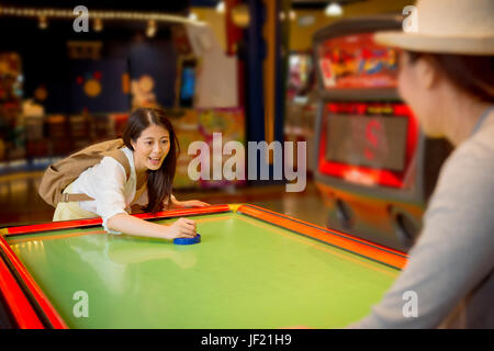 asian pretty female students going to the playground playing the table hockey game with sister friends after school class study together in the free t Stock Photo