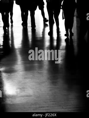 Group of people silhouettes and shadows walking in the dark city passage in black and white Stock Photo