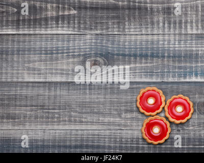 Three cookies with cherry jelly filling lie on a wooden table. View from above. There is space for text on the left Stock Photo
