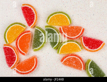 Multicolored fruit jelly in the form of fruit scattered randomly on a gray table top Stock Photo