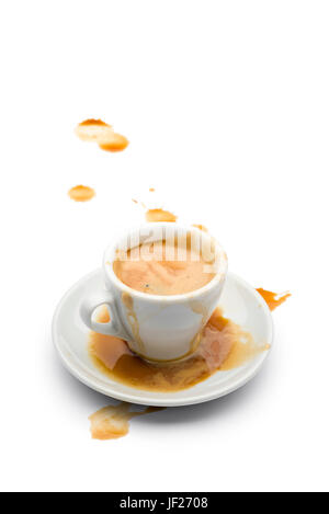 full cup of coffee with coffee spilled on the saucer and on the white table. Stock Photo