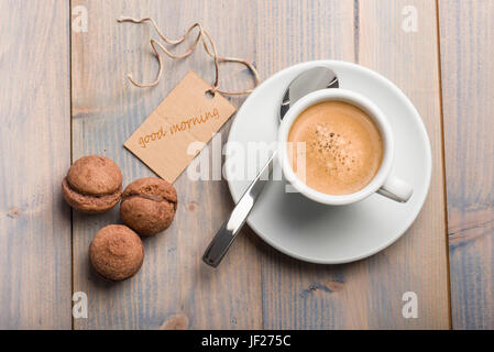 cup of coffee on wooden table with chocolate cookies and card that says good morning. Stock Photo