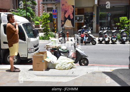 A man recycling items loads up his scooter to carry it off to sell. June 30, 2017, Taiwan Stock Photo