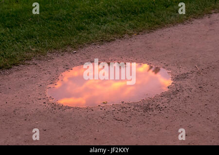 Reflection of sunset in puddle on track Stock Photo