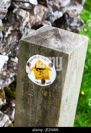 A waymarker on a wooden post with a yellow arrow showing the way on the Manifold Valley circular walk Ilam Staffordshire England UK Stock Photo