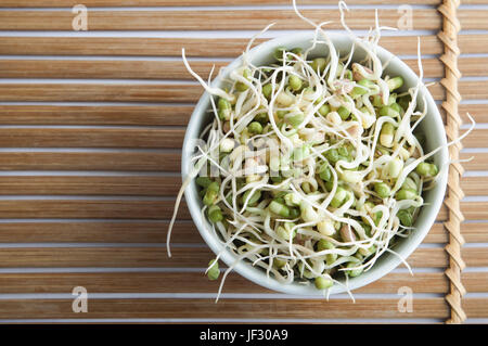 Overhead shot of a bowl of mung beansprouts, standing on a slatted bamboo mat. Stock Photo