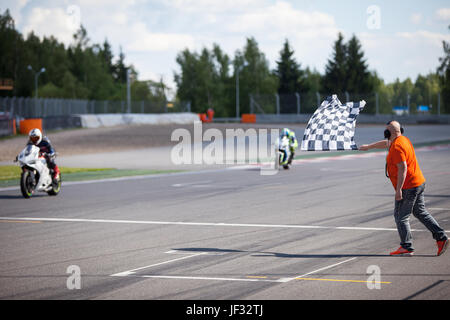 Man holding and waving the checkered flag at the finish of the race Stock Photo