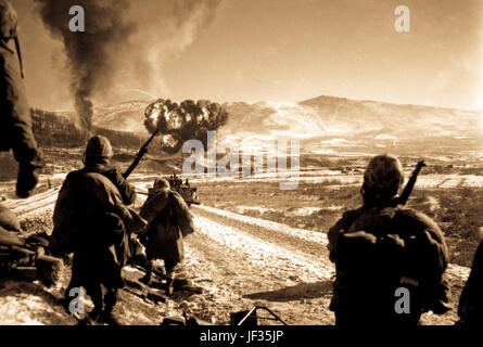 U.S. Marines move forward after effective close-air support flushes out the enemy from their hillside entrenchments.  Billows of smoke rise skyward from the target area.  Hagaru-ri.  December 26, 1950.  Photo by Cpl. McDonald.  (Marine Corps) Stock Photo